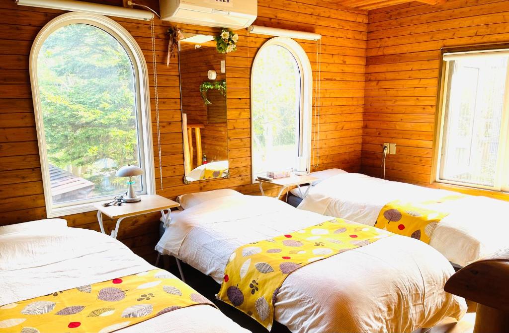 3 camas en una habitación con 3 ventanas en 民泊JOYFUL天然温泉付きログハウス, en Shiraoi