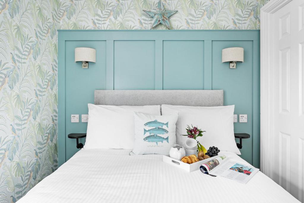 a bedroom with a white bed with a blue headboard at Sandway House in Torquay