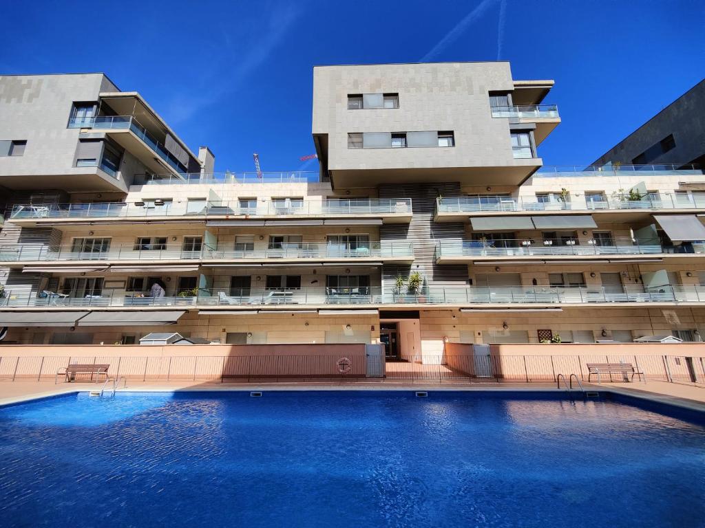 a building with a swimming pool in front of a building at Badalona Beach Apartment in Badalona