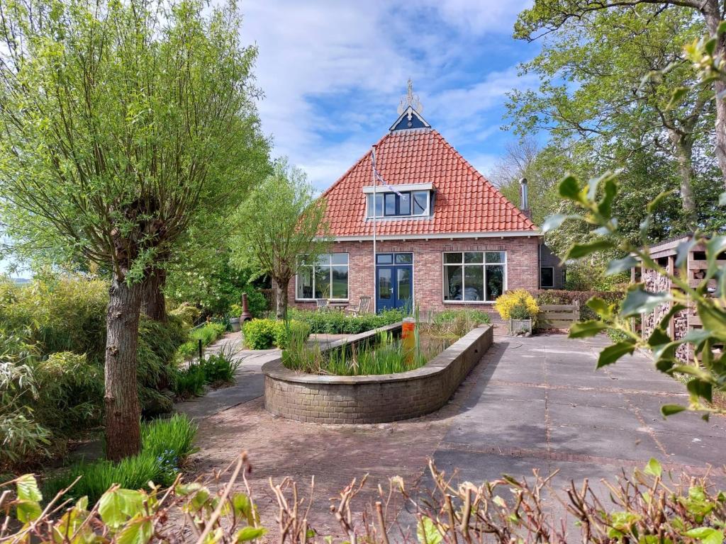 una casa de ladrillo con techo rojo en Luxe gastenverblijf in het hart van Friesland, en Akkrum