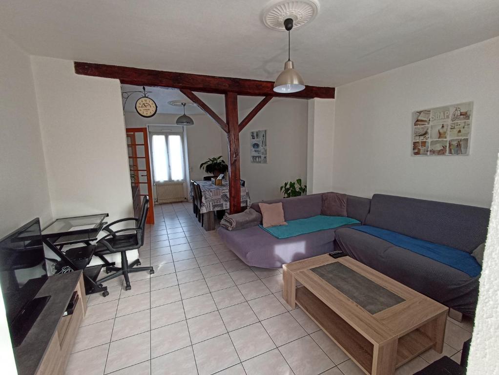 ein Wohnzimmer mit einem Sofa und einem Tisch in der Unterkunft Maison de ville de 95M2 in Montmorillon