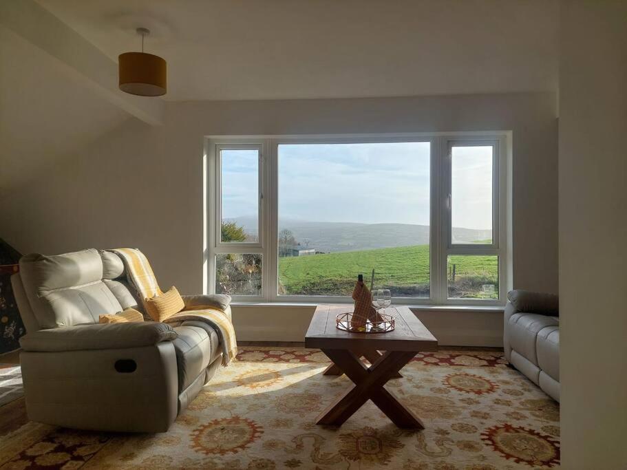 ein Wohnzimmer mit einem Sofa, einem Tisch und einem Fenster in der Unterkunft Deerpark Cottage, Inistioge, Kilkenny in Inistioge