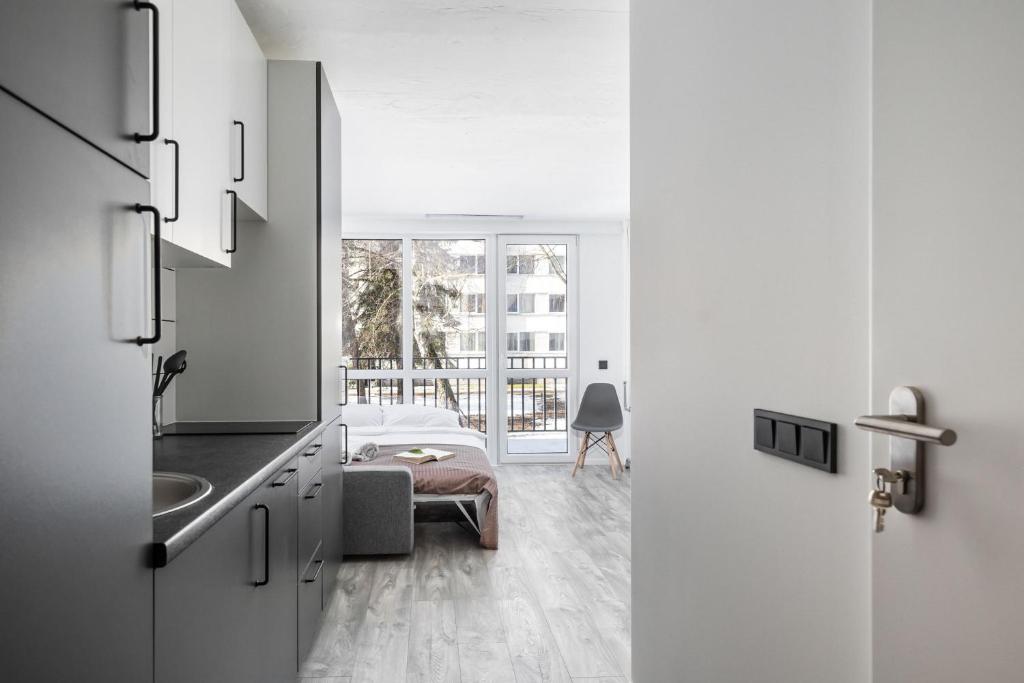 a kitchen with a sink and a room with a bed at River To The City - Studio 7b Apartment in Vilnius