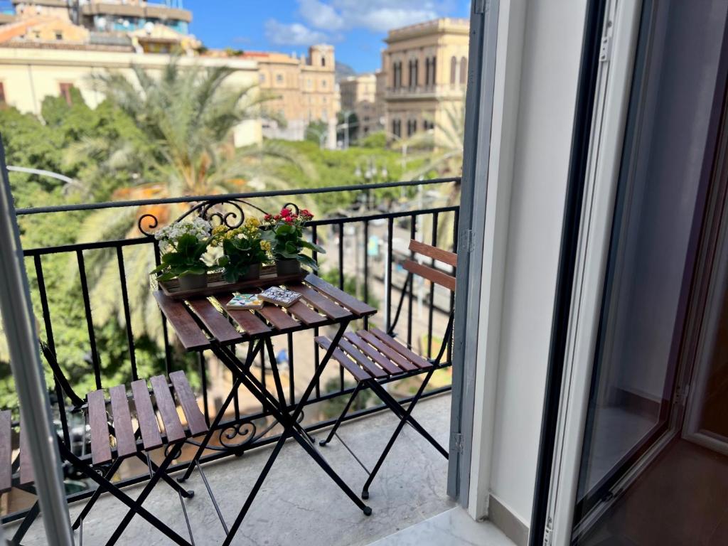 einen Balkon mit 2 Stühlen und einem Tisch mit Blumen darauf in der Unterkunft Case Orlando_a city center Sicilian treat in Palermo