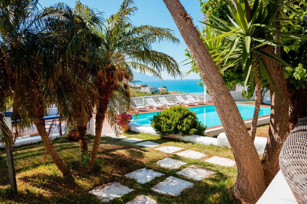 un complejo con piscina y palmeras en B&B Scacciapensieri, en Castellammare del Golfo