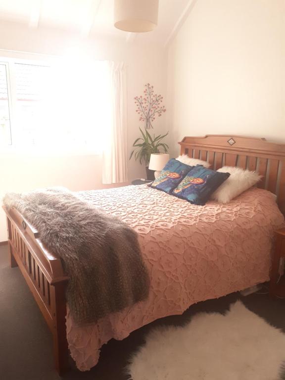 a bedroom with a wooden bed with pillows and a window at Oasis On Oxford in Dunedin