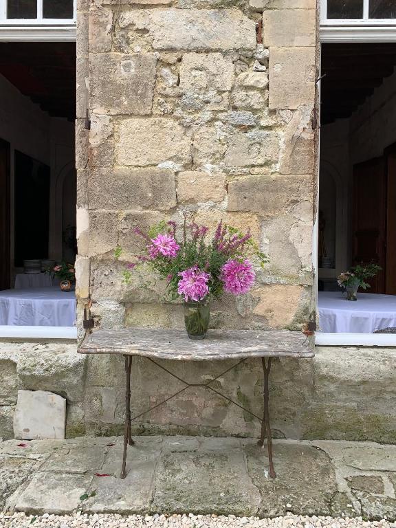 a table with a vase of pink flowers on it at La Maison Saint Joseph in Crépy-en-Valois