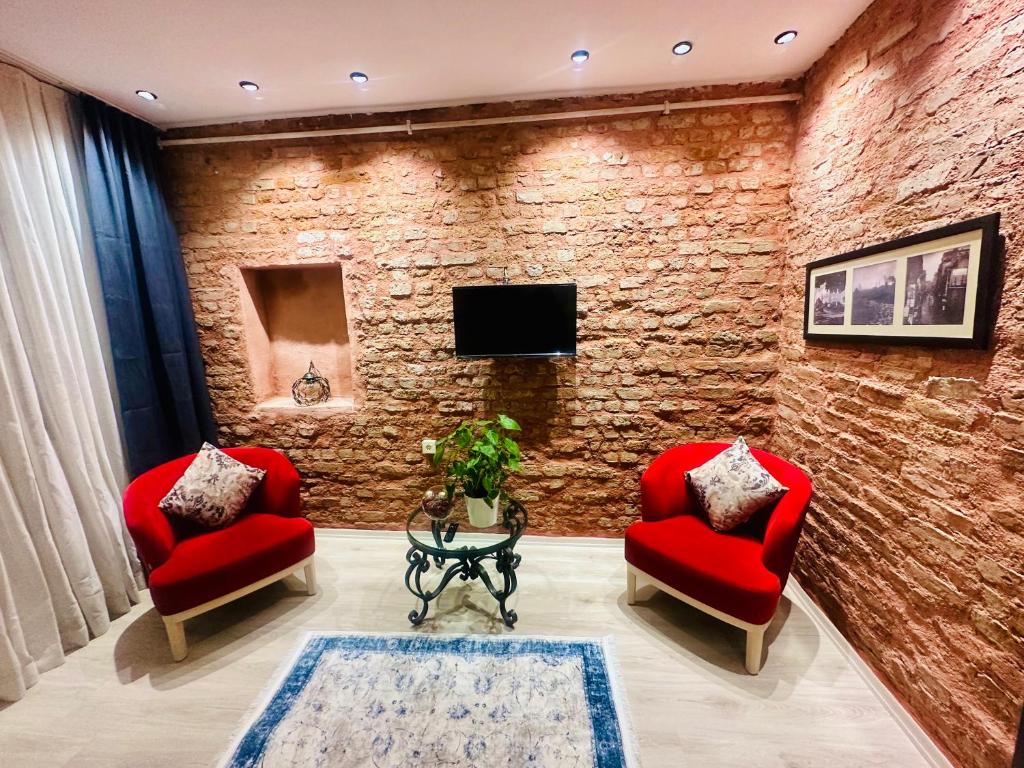 uma sala de estar com duas cadeiras vermelhas e uma parede de tijolos em Taksim studio em Istambul