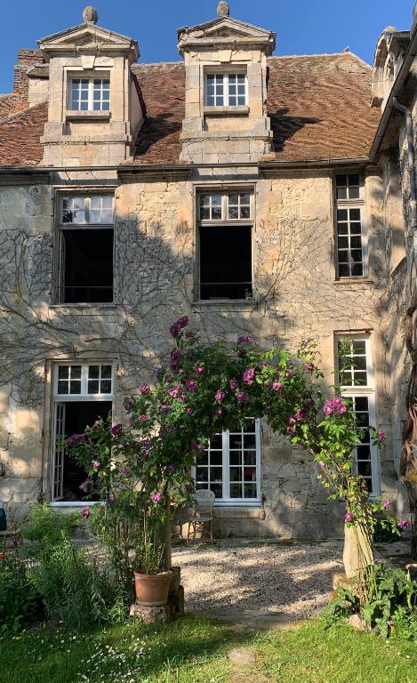 an old stone house with flowers in front of it at La Maison Saint Joseph in Crépy-en-Valois