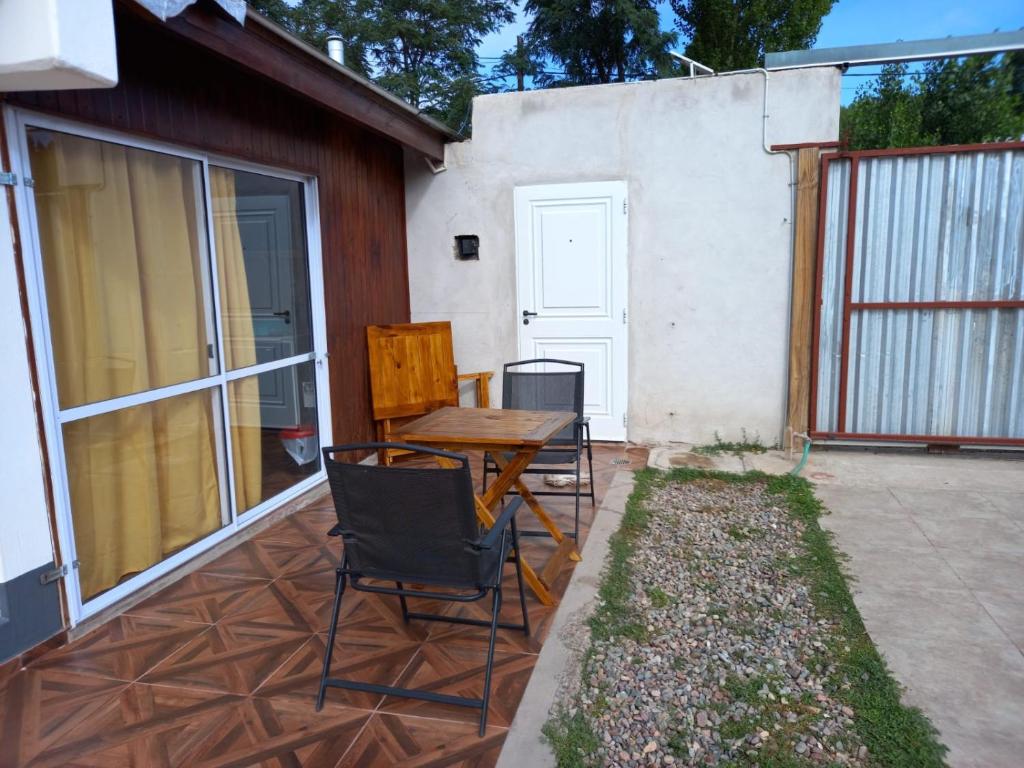 un patio con una mesa de madera y sillas. en Departamento LA LILI en Uspallata