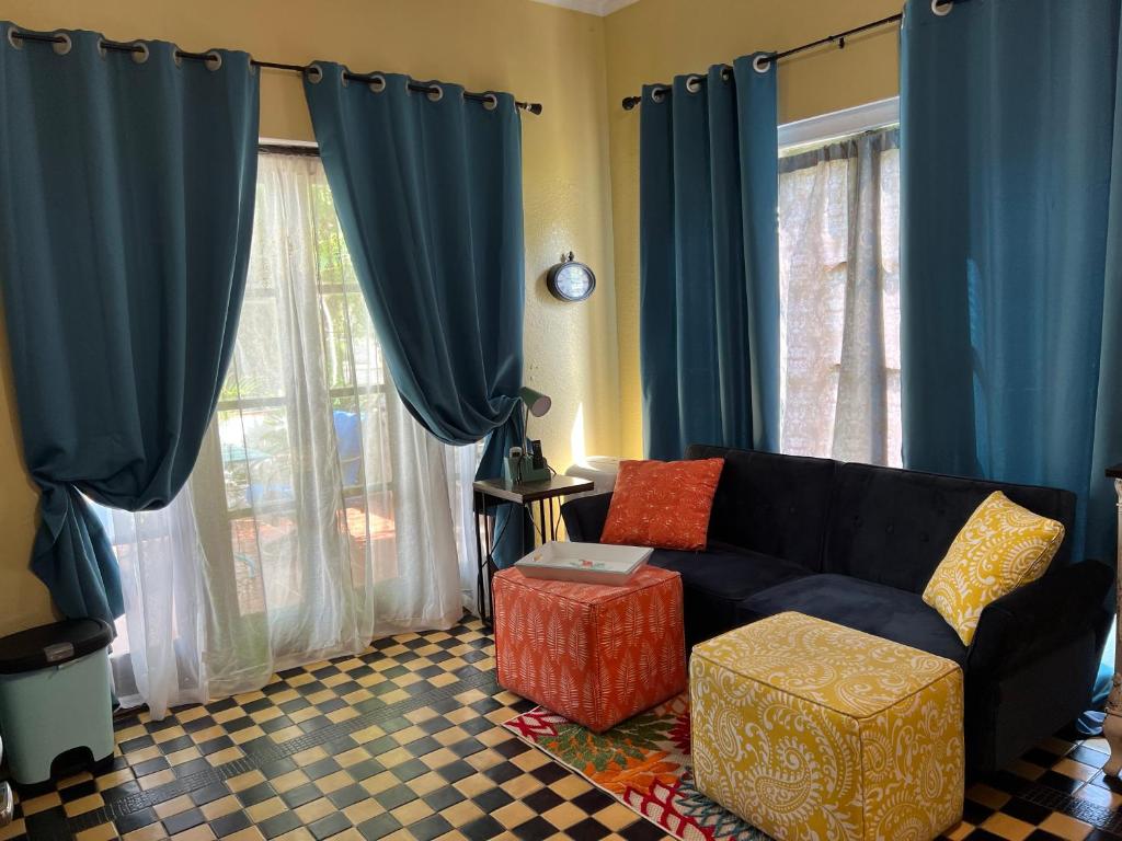 ein Wohnzimmer mit einem schwarzen Sofa und blauen Vorhängen in der Unterkunft Design District Wynwood Studio in Miami
