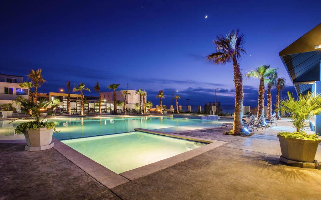 - une piscine de nuit avec des palmiers et des bâtiments dans l'établissement Beautiful house at Rosarito beach, à San Antonio del Mar