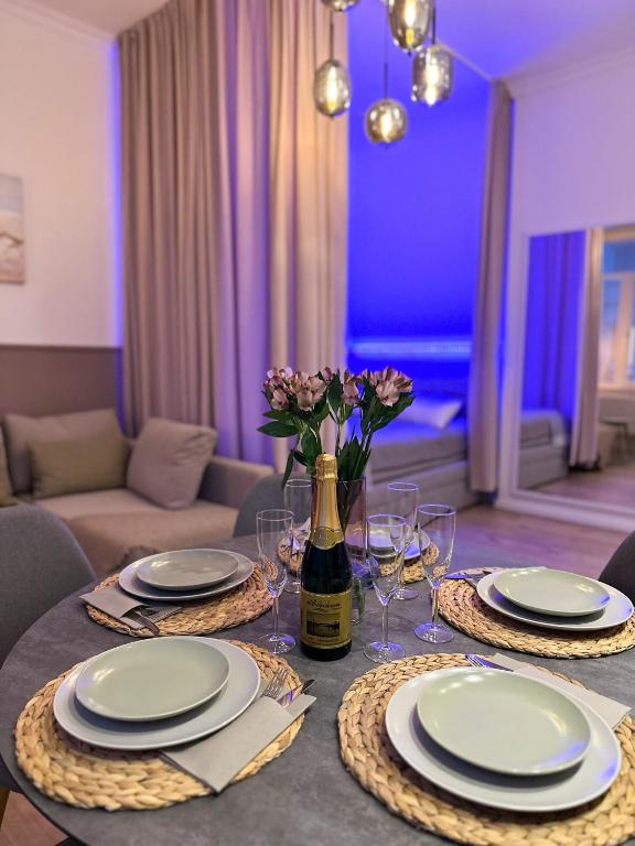 a table with plates and a bottle of wine and flowers at Ferienwohnung Strandläufer in Wilhelmshaven