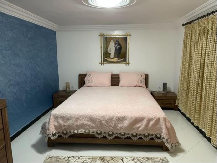 1 dormitorio con 1 cama grande con almohadas rosas en Appartement chems, en Oualidia