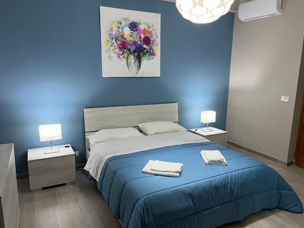1 dormitorio azul con 1 cama con 2 toallas en The Artists, en Acireale