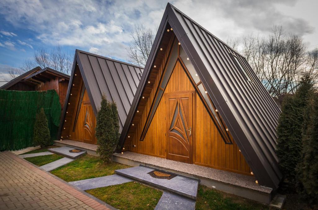 un gran edificio de madera con 2 grandes puertas de madera en Arhico Cabins en Satu Mare