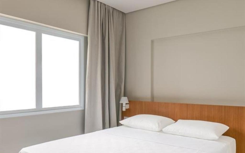 ein Bett mit zwei Kissen und ein Fenster in einem Zimmer in der Unterkunft Salinas Exclusive Resort in Salinópolis