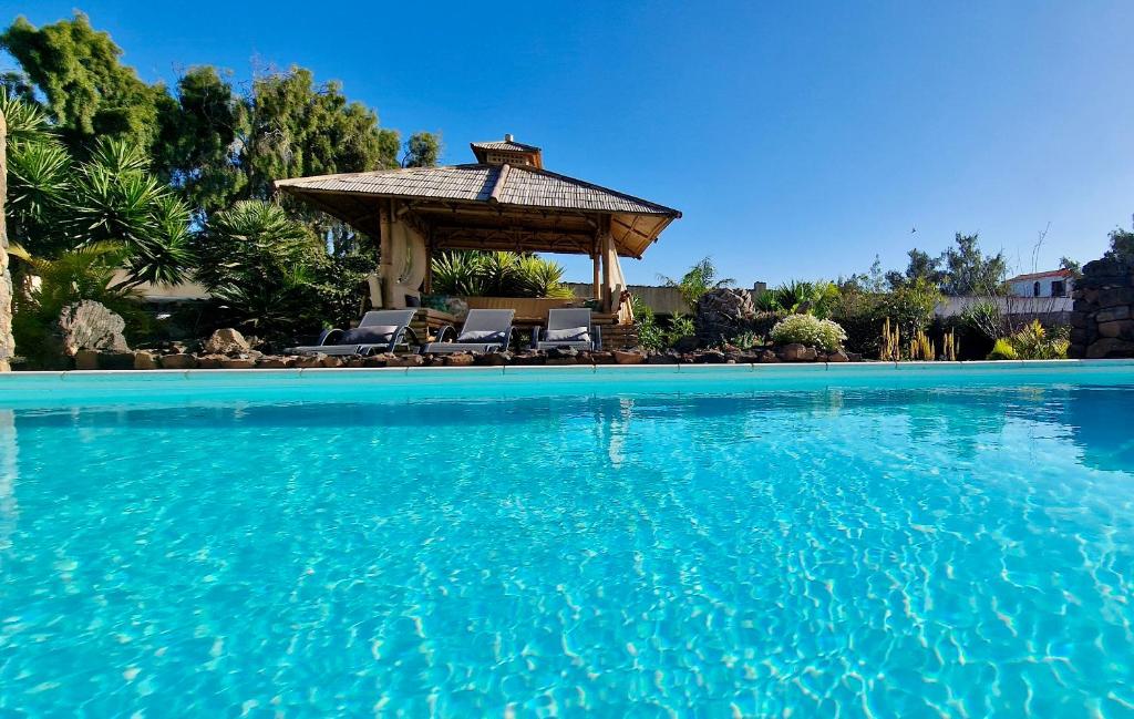 a swimming pool with a gazebo and blue water at Casa YUKKA villa with heated pool in Lajares