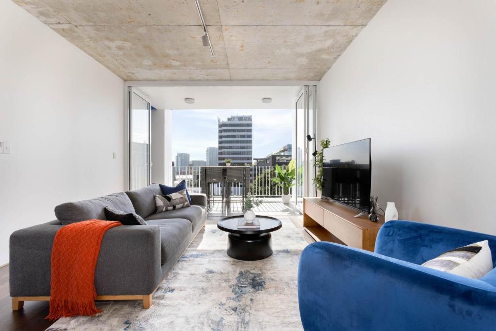 a living room with a couch and a tv at The Chromatic Apartments by Urban Rest in Sydney