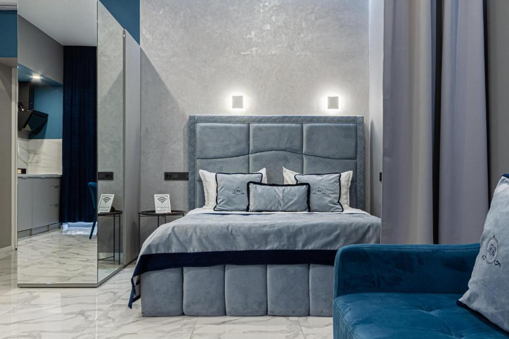 ein Schlafzimmer mit einem großen Bett und einem blauen Sofa in der Unterkunft Family Residence Boutique Apartments in Lwiw