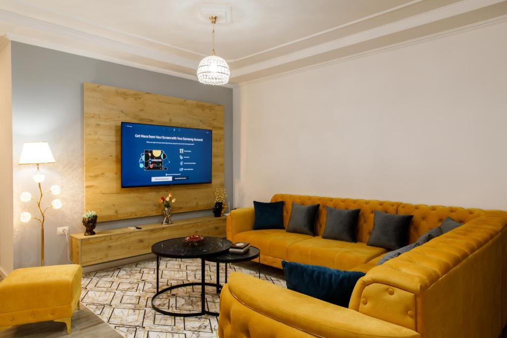 a living room with a yellow couch and a tv at The Luxe Apartments in Gjirokastër