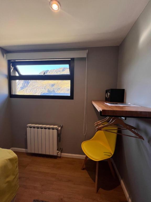 Habitación con escritorio y silla amarilla. en Desierto Suites en El Chaltén