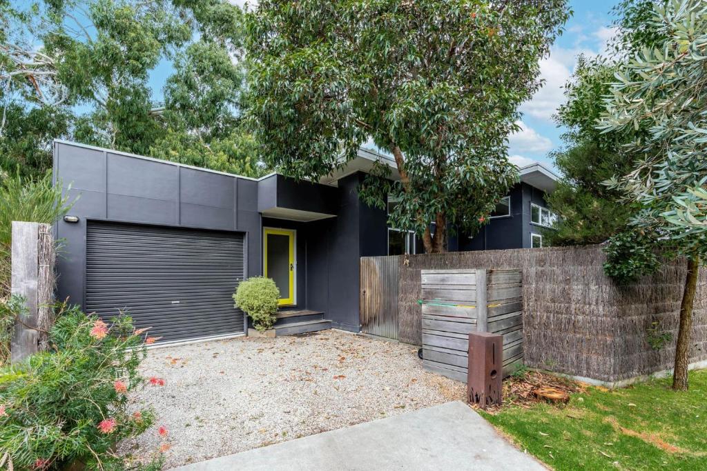 a black house with a fence at The Yellow Door Inverloch in Inverloch