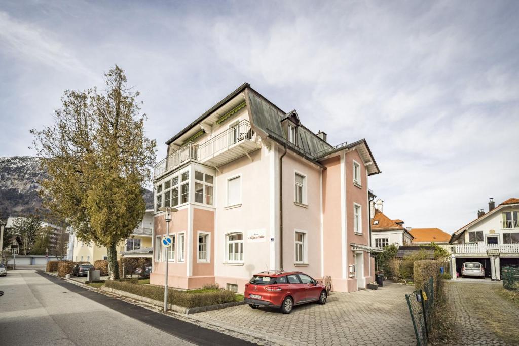 un coche rojo estacionado frente a una casa rosa en Haus Alpenruhe en Bad Reichenhall