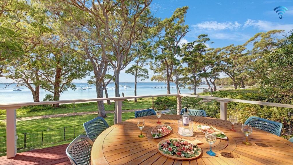 a table on a deck with a view of the beach at Tradewinds in Callala Bay