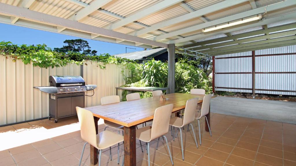 un patio con tavolo e sedie in legno e griglia di Cypress Cottage 26 Cypress Street Evans Head a Evans Head