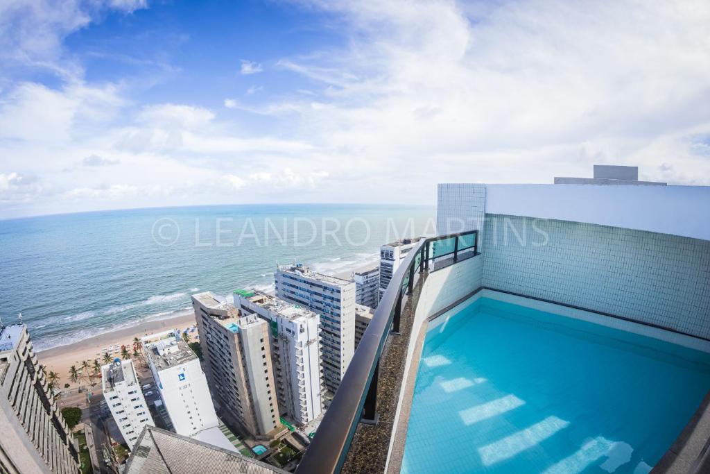 a swimming pool on top of a building next to the beach at Apartamento Royale na praia de Boa Viagem in Recife