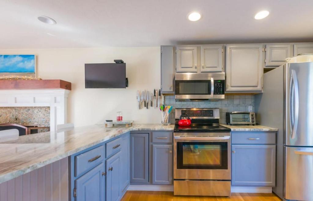 une cuisine avec armoires bleues et appareils en acier inoxydable dans l'établissement 17 Woodland Avenue Mashpee Cape Cod - - The Cape Escape, à Mashpee