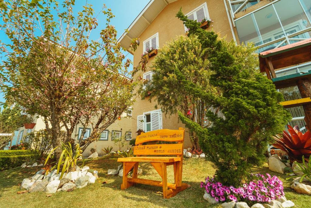 una panchina di legno seduta di fronte a una casa di Apartamento Sobre as Nuvens a Campos do Jordão