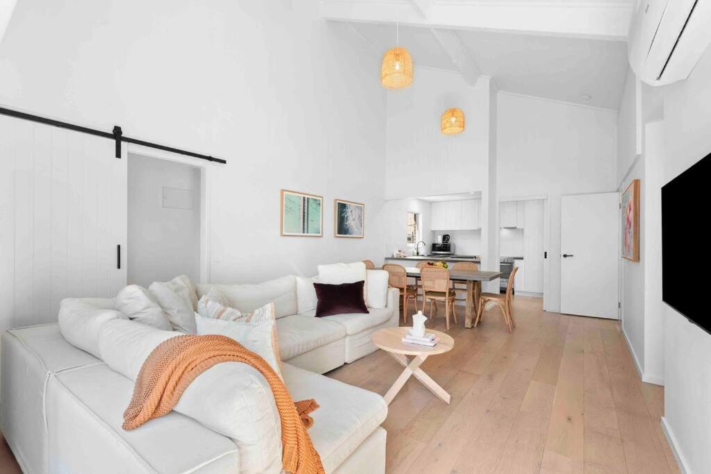 a white living room with a white couch and a table at So Beachy! 200m to the beach or shops! Sleeps 8 in Ocean Grove