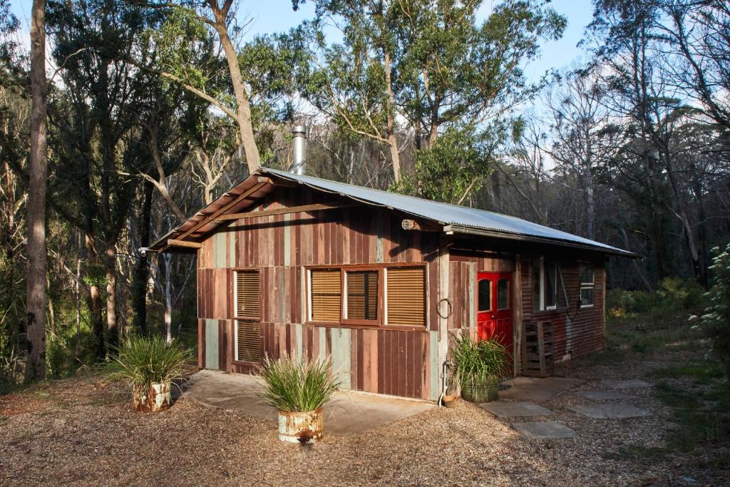 un piccolo edificio in legno con una porta rossa di Monga Mountain Retreat a Reidsdale