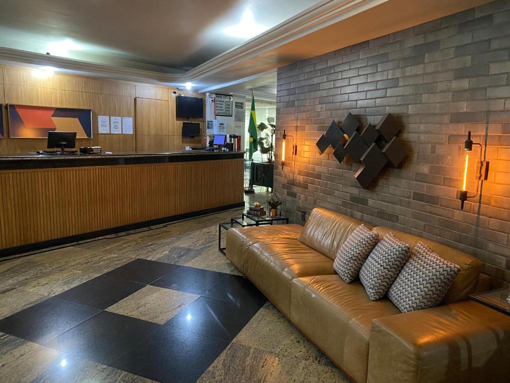 a leather couch in a lobby with a brick wall at Hotel Caiçara in Cachoeiro de Itapemirim
