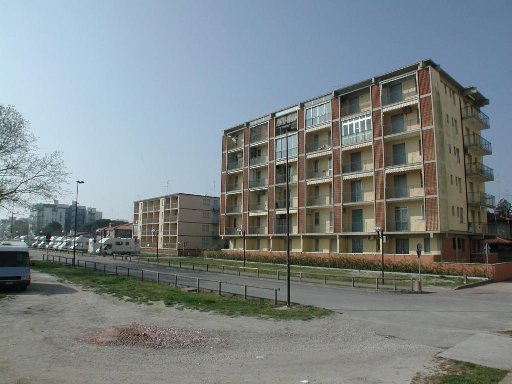 a large brick building next to a parking lot at Appartamento Aurora in Lido degli Estensi