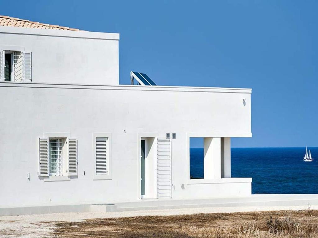 a white house with the ocean in the background at Belvilla by OYO Capo Passero Dieci in Portopalo