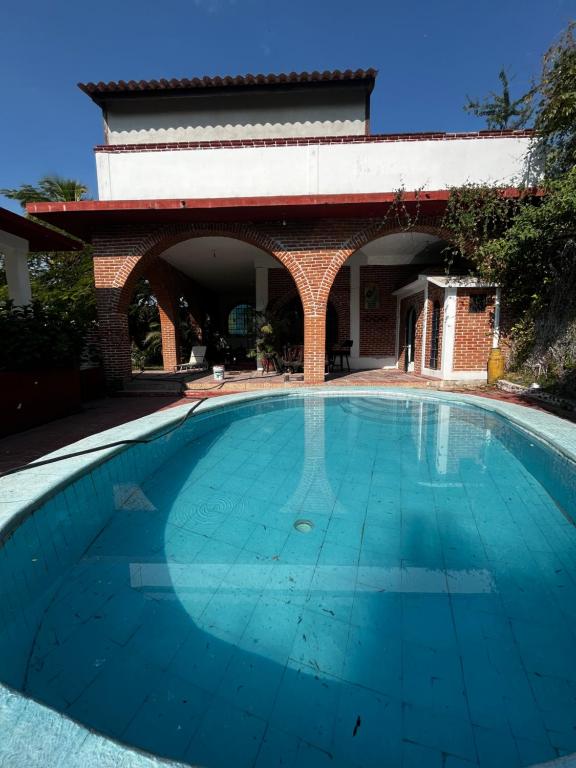 una grande piscina blu con un edificio in mattoni di La casa club a Oacalco
