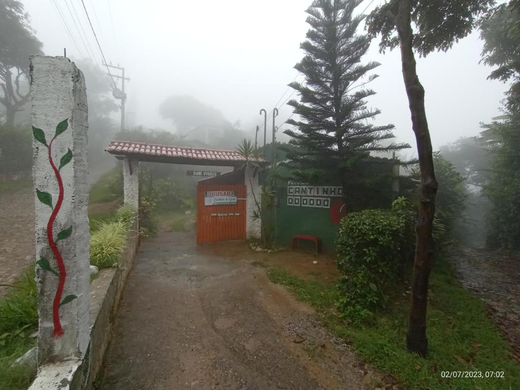 una strada nebbiosa con un edificio e un albero di Pousada Cantinho do Dodó a Mulungu