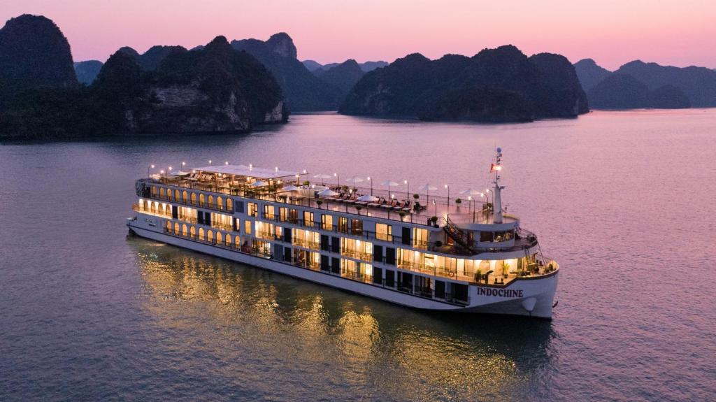 a cruise ship in the water with mountains in the background at Indochine Cruise Lan Ha Bay Powered by ASTON in Ha Long