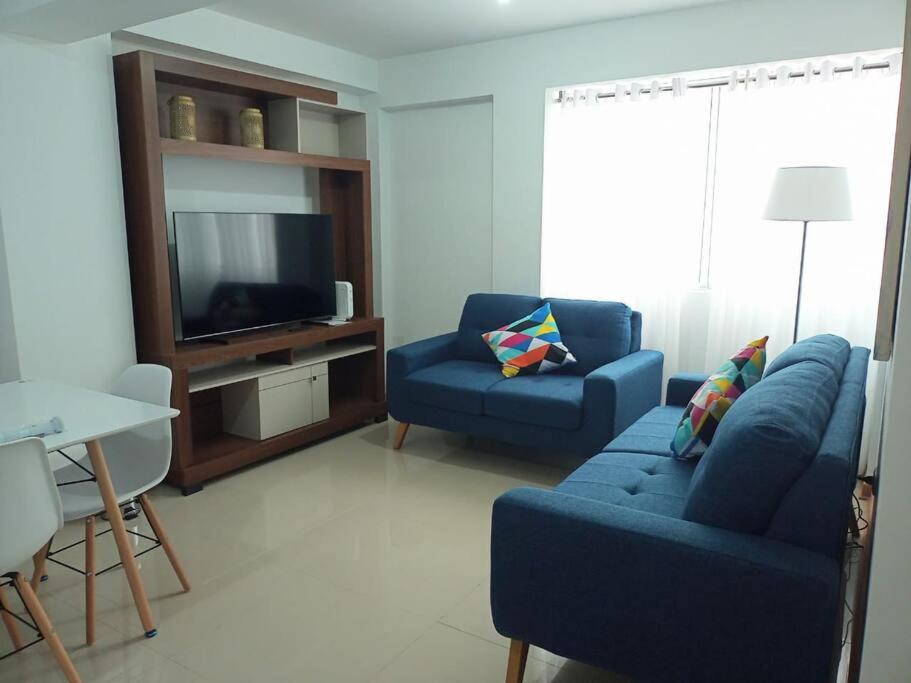 a living room with a blue couch and a tv at Elegante y acogedor departamento entero # 3 in Víctor Larco Herrera