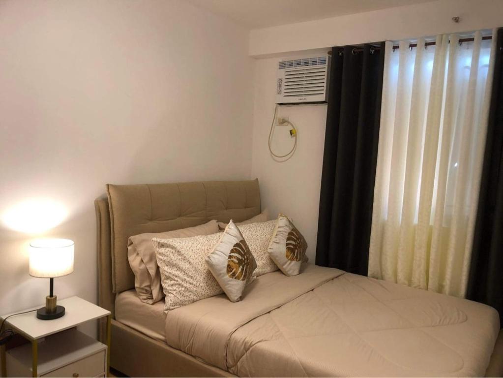 ein kleines Schlafzimmer mit einem Bett mit Kissen darauf in der Unterkunft Arezzo Condo Staycation in Davao City