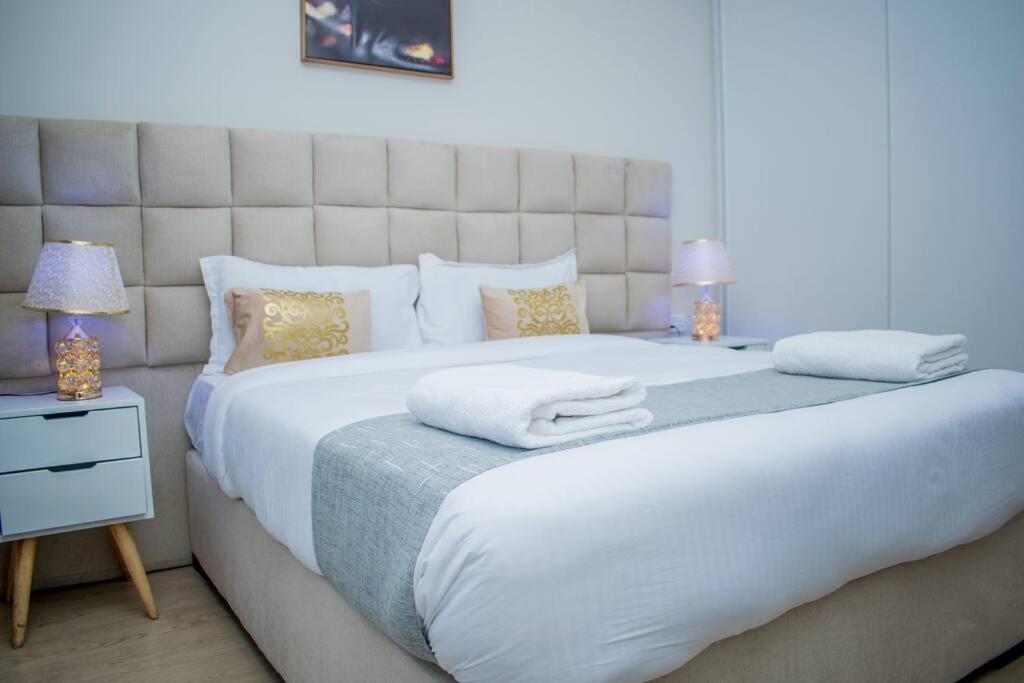 een slaapkamer met een groot wit bed met 2 lampen bij Elite Residences by Bednbeyond O72195O3I9 in Nairobi