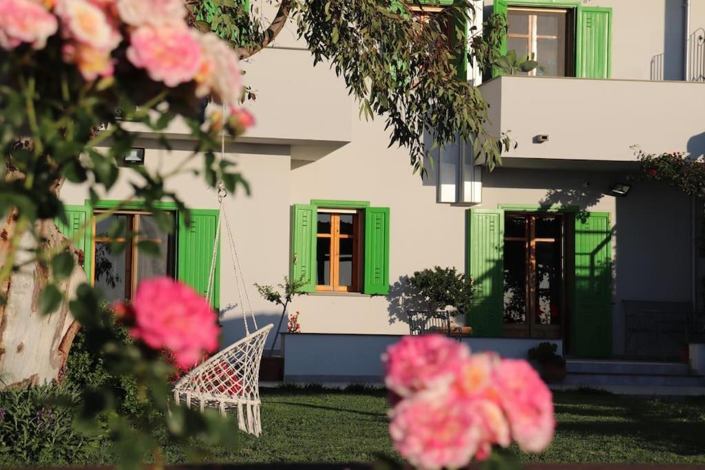 una casa con persianas verdes y flores rosas en Villa Timpone, en Guardavalle