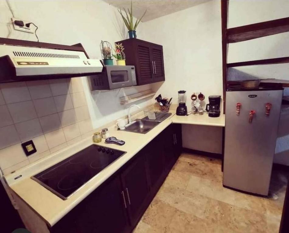 una pequeña cocina con fregadero y nevera. en Bonita casa Moon Penthouse en Cancún, en Cancún