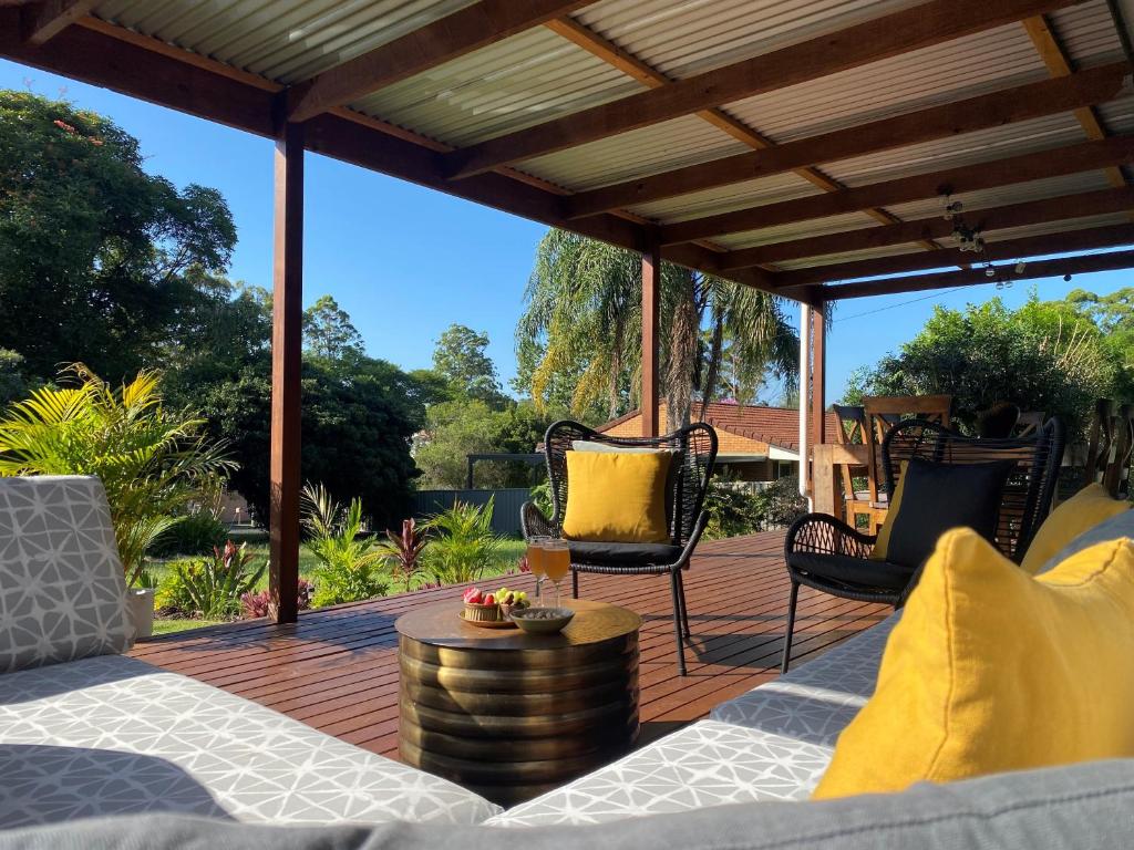 a patio with a table and chairs on a wooden deck at Quirky little 2 bedroom in quiet cul-de-sac in Kempsey