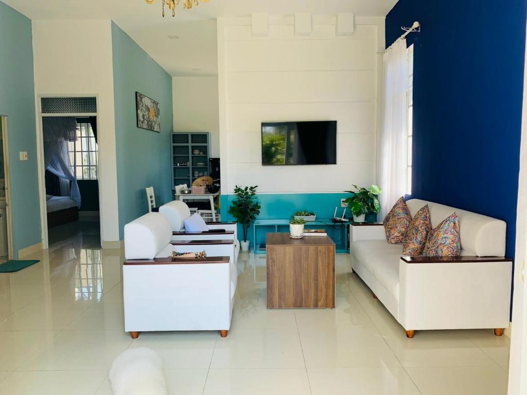 uma sala de estar com dois sofás brancos e uma parede azul em Mon House em Bao Loc
