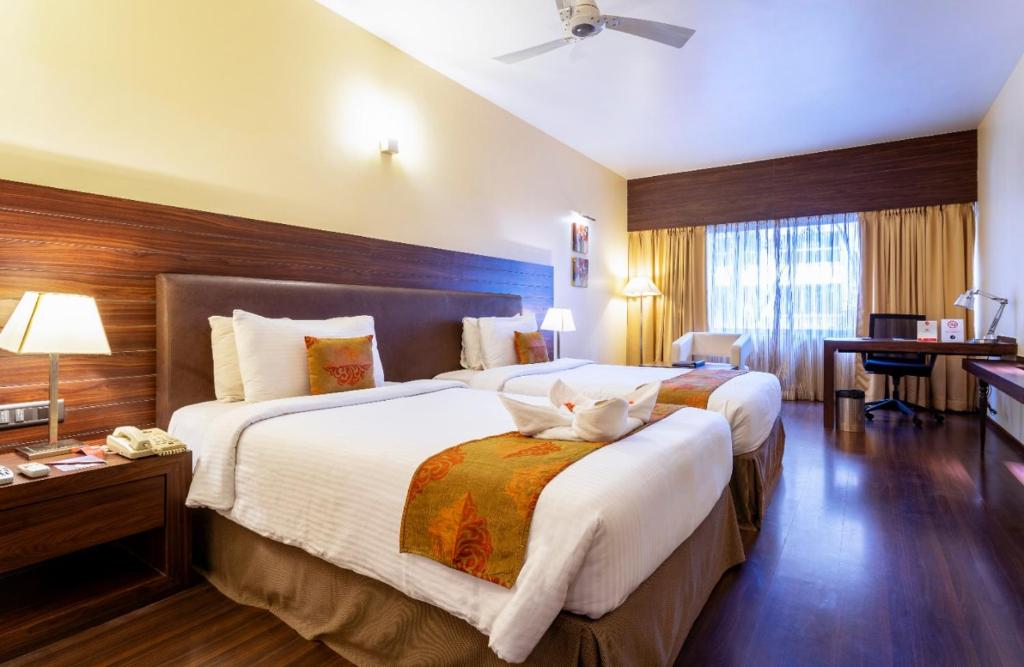 a hotel room with two beds with a cat laying on the bed at THE WOODROSE in Bangalore