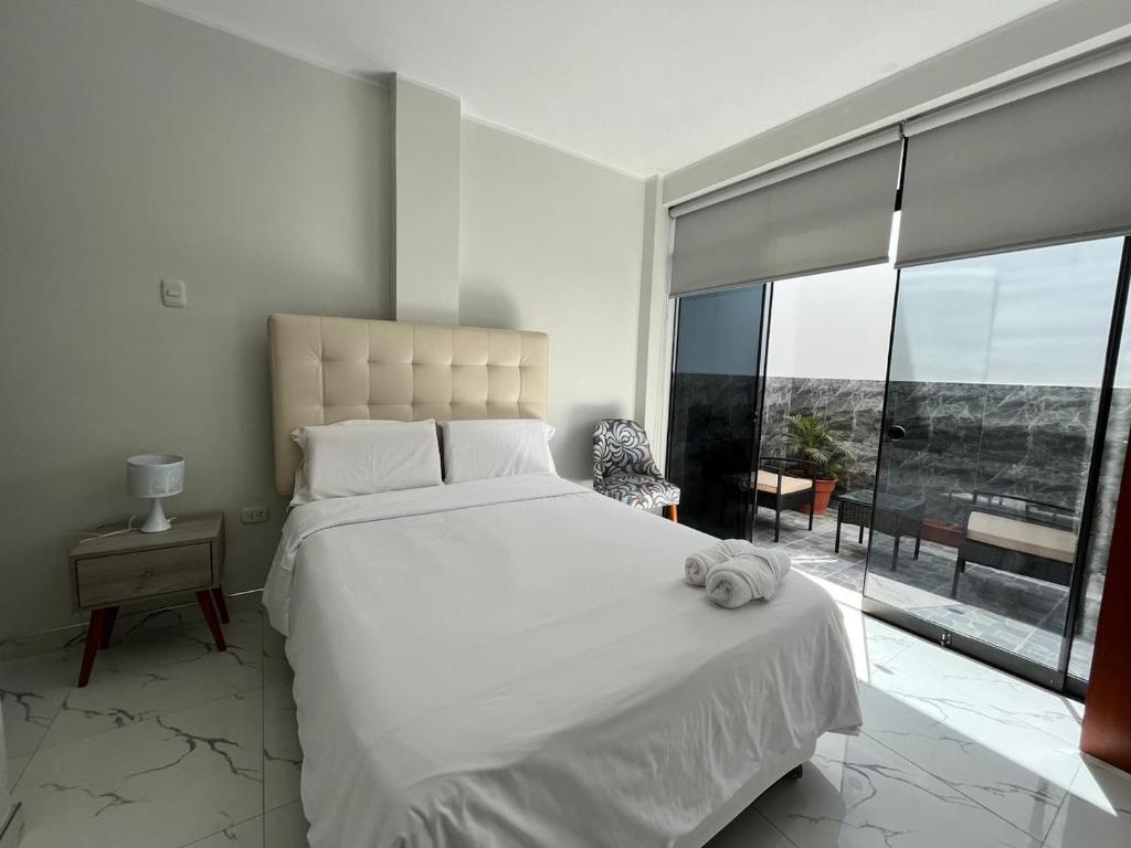 a bedroom with a large white bed and a large window at Makai - Nayarak Paracas in Paracas